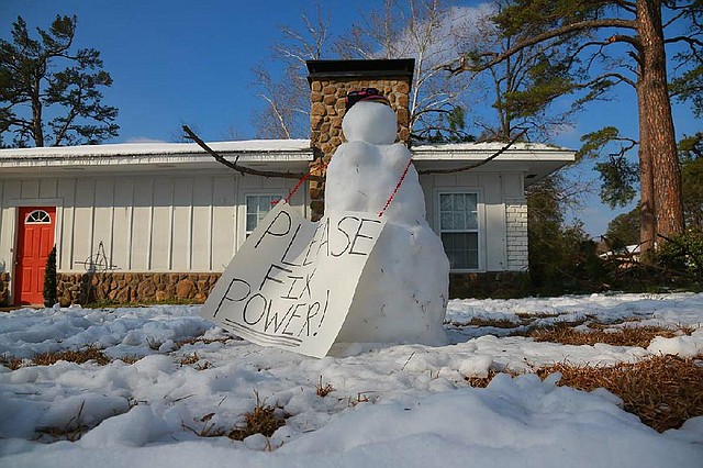 A snowman makes a plaintive plea for power Saturday at a Little Rock home on McAdoo Street just north of Markham. 