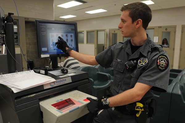 Deputy Mike Nugent shows on Friday how the Benton County Jail’s fingerprinting equipment works. 