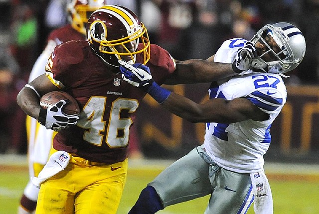 Washington Redskins running back Alfred Morris (left) stiff-arms Dallas Cowboys strong safety Eric Frampton during the second half Sunday night in Landover, Md. Morris rushed for 200 yards and three touchdowns as the Redskins clinched the NFC East title with a 28-18 victory. 