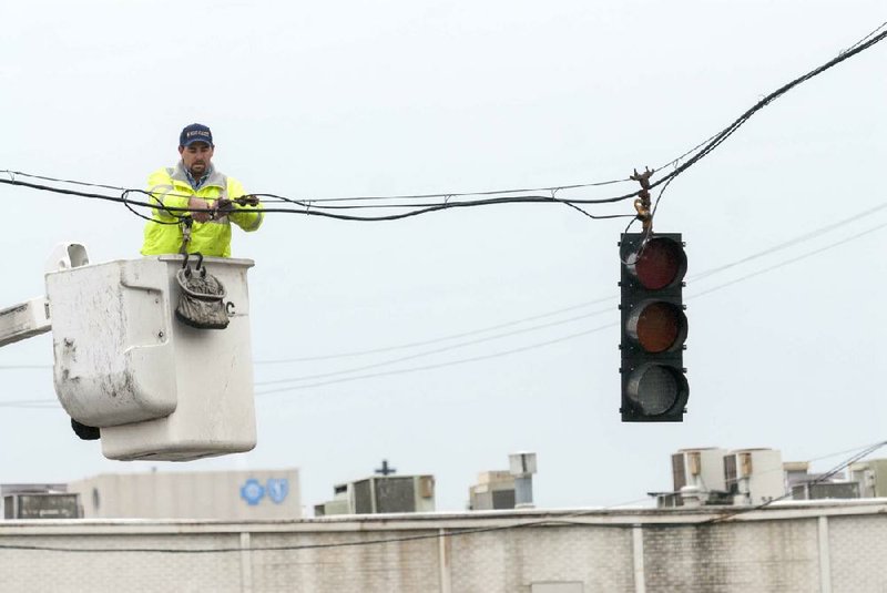 Daniel Craine, with the Little Rock Public Works Department, installs a new stoplight at the intersection of Ninth and Scott streets Monday morning to replace one knocked down during a traffic accident on slick roads last week. 