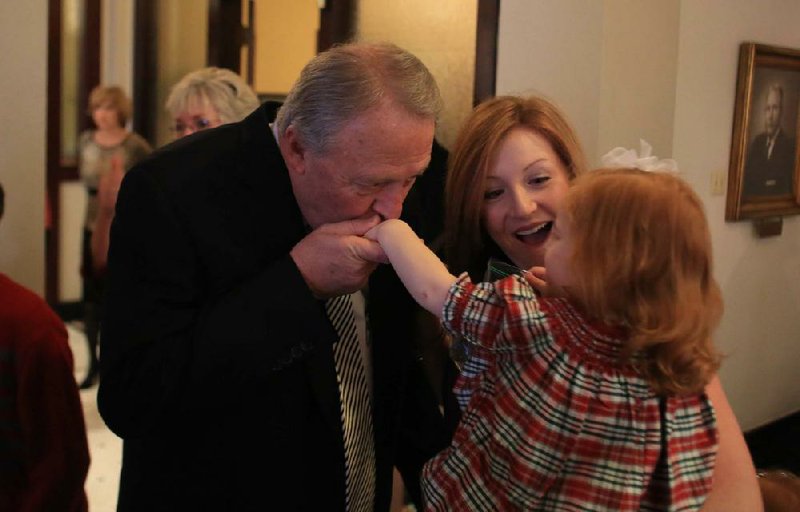 Joe A. Smith kisses the hand of his granddaughter Kate Walker, 2, held by her mother and Joe's daughter Lauren. a short time before Smith took the oath of office to be mayor of North Little Rock from Judge Randy Morley at City Hall Tuesday.