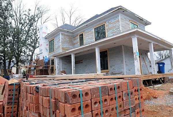 Workers remodel a house Friday at Southwest C and Southwest Fourth streets in Bentonville. 