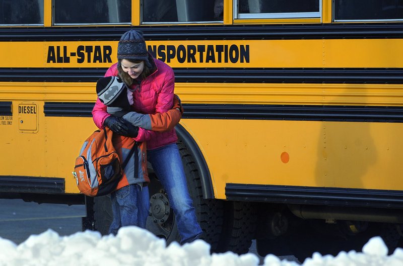 A woman hugs a child before he boards a bus on the first day of classes after the holiday break, in Newtown, Conn., on Wednesday, Jan. 2, 2013. Children from Sandy Hook Elementary School returned to school Thursday in the neighboring town of Monroe. 
