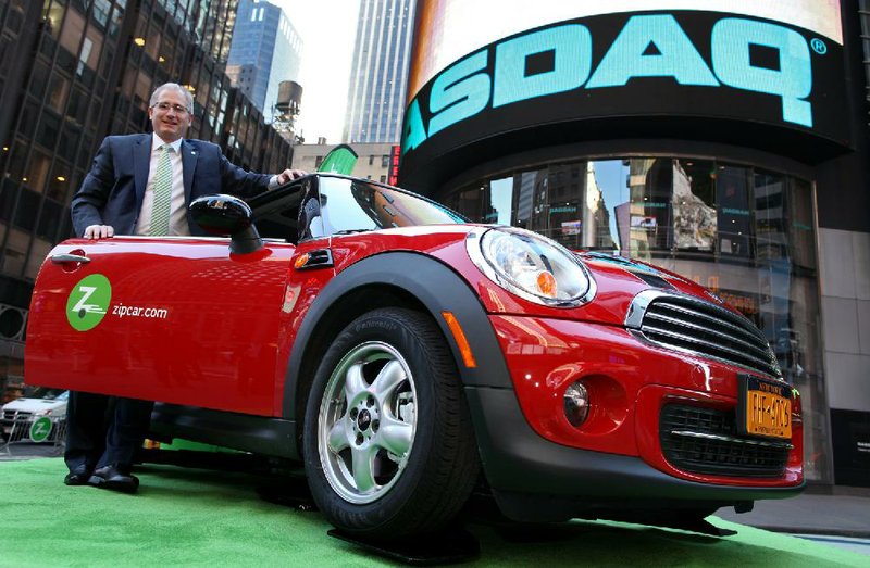 FILE - In this April 14, 2011 file photo provided by Zipcar.com, Zipcar Chairman and CEO Scott Griffith stands with a Zipcar Mini-Cooper before the opening bell at the NASDAQ Market Site in New York. Avis is buying Zipcar for $491.2 million, expanding its offerings from traditional car rentals to car sharing services. The boards of both companies unanimously approved the buyout. (AP Photo/Zipcar.com, Craig Ruttle, File)