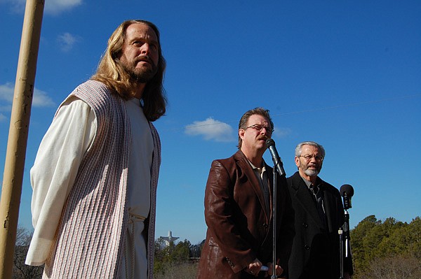 Rick Mann (left), who has portrayed Jesus at the Great Passion Play near Eureka Springs since 1997, looks on as Randall Christy (center), president of The Gospel Station Network, and Keith Butler (right), chairman of the Elna M. Smith Foundation, announce Thursday that they had raised enough money to continue operating the religious attraction. 