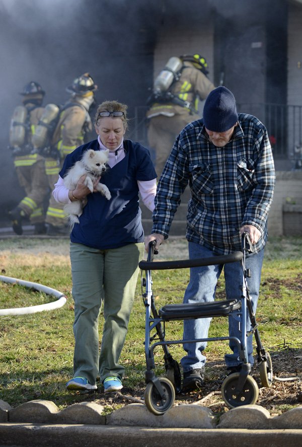 Kim Benham, left, leads John Logston and his dog “Tuffy” away from his home Thursday as Bentonville firefighters work to contain a fire that broke out in the garage of Logston’s home at 308 Magnolia Drive in Bentonville. Logston and wife Charleta were uninjured in the fire. Benham, a home health care nurse, alerted the Logstons to the fire when she arrived at the home and discovered smoke coming from the garage.
GOOD TIMING 