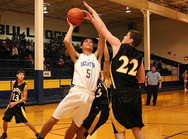  Decatur sophomore forward Mario Urquidi takes a shot under the basket over Hackett's Buddy Nichols during play in Decatur on Friday night.