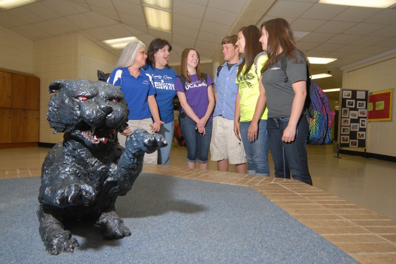 Conway High School teachers, Beth White, from the left, and  Jeani Johnson, along with former students Natalie Faught, Corey Robichaud, Christina Johnson and Cheyanne Sutton, chat in part of the old Conway High School before its demolition near a small statue of the school's mascot, the Wampus Cat. An unveiling of a 6-foot-tall bronze Wampus Cat statue is scheduled for 4 p.m. Tuesday in front of the James H. Clark Auditorium on the new high school campus.