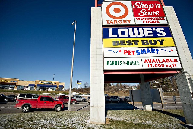 Cars pass a sign for a Target store outside a shopping mall in Peoria, Ill., this week. Target plans to promote its groceries and home products in an advertising campaign this year. 