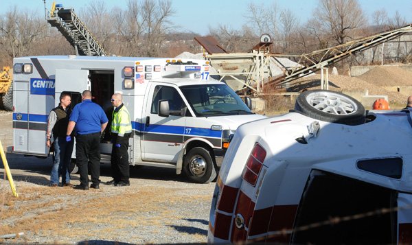 Central Emergency Medical Service employees work Friday to treat a motorist injured after the Ford Mustang he was traveling in left the roadway and overturned on Van Asche Drive in Fayetteville. 