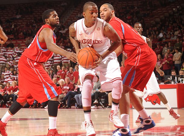 NWA Media/ANDY SHUPE -- Arkansas sophomore guard BJ Young, center, drives through the lane as Delaware State sophomore forward Tyshawn Bell, right, and junior forward Casey Walker, left, defend Saturday, Jan. 5, 2013, during the first half of play in Bud Walton Arena in Fayetteville.