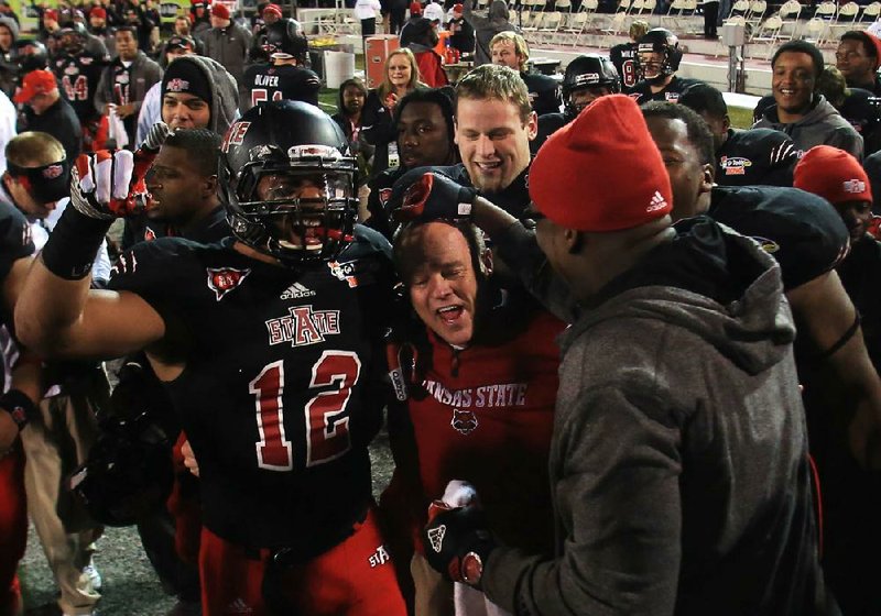 Interim Arkansas State coach John Thompson (center) celebrates the Red Wolves’ victory in the GoDaddy.com Bowl on Sunday with Kyle Coleman (12) and others. Thompson now returns to his duties as defensive coordinator for new coach Bryan Harsin. 