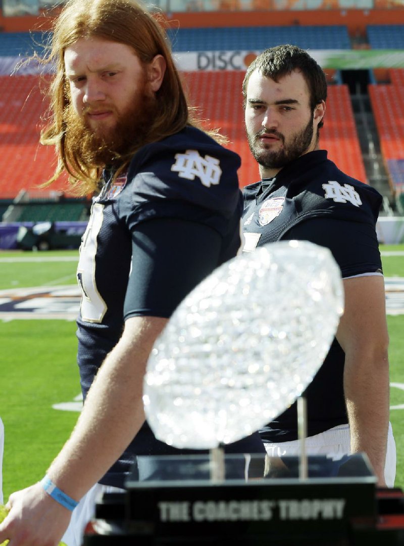 Notre Dame players Conor Hanratty and Tony Springmann eye The Coaches’ Trophy during media day Saturday in Miami. 