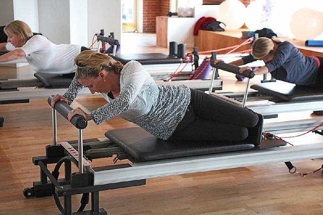 During a group Reformer class in IM=X Pilates at Pavilion in the Park, (from left) Tricia Smith, Laura Herron and Shanti Halter do push-ups in a rotated stretch, which allows their pectoral muscles to carry the main challenge. 