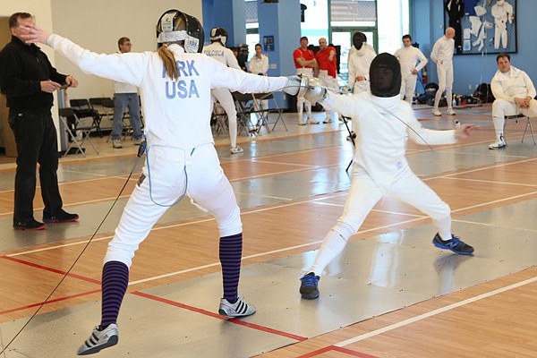 Elizabeth Kirk, left, competes in a fencing match at the Northwest Arkansas Fencing Center in Bentonville. The Kirk family, which also includes Elizabeth’s 15-year-old twin sister, Olivia, operates the center, which currently has about 75 fencers. 
