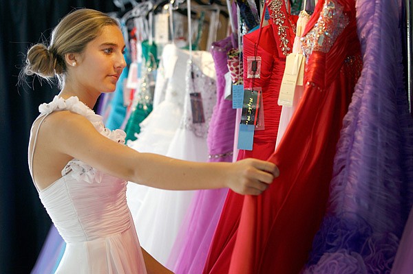 Jordan Maass, 15, looks over a selection of dresses Friday at White Dress Boutique in downtown Rogers. Jordan, a Rogers High School sophomore, was looking for a dress for Colors Day Court. 