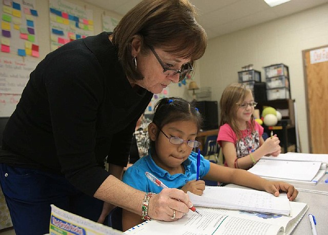 Third grade teacher Johnnie Brock checks the work of students Bernice Antunez (middle), 8, and Trista Black, 9, at De Queen Elementary School. 