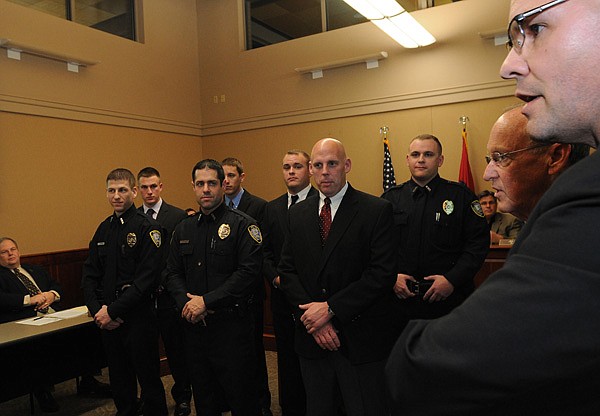 Seven new Bentonville police officers, from left, Kevin Albert, Ben Peters, Andy Oliver, Nicholas Brown, Andrew Corbett, James Boothman and Adam Corbett, were sworn in Tuesday night at the Bentonville City Council meeting. Mayor Bob McCaslin, second from right, swore the officers in at the meeting. Police chief Jon Simpson, right, congratulated the new officers after the ceremony. 