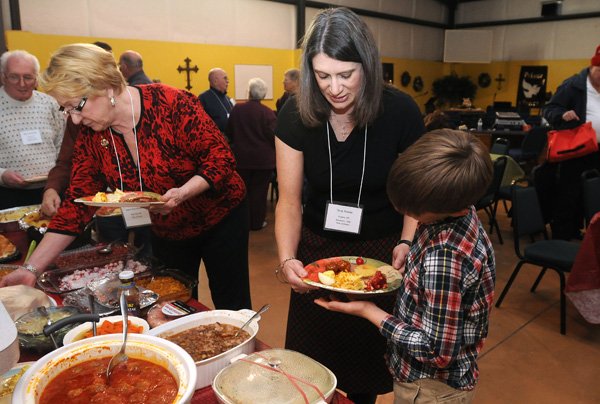 Irene Boomhower, left, dishes up her plate as Tena Reese, center, helps her son, Caleb Reese, 11, with his plate of food at a recent Northwest Arkansas Ostomy Support Group meeting at Oak Manor Christian Church in Fayetteville. About 35 people attend the monthly meetings, designed to offer education and support for those living with ostomies. 