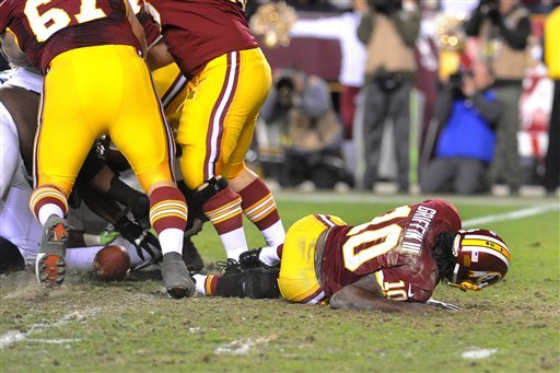 The ball is loose, as Redskins quarterback Robert Griffin III lays on the field after fumbling the snap from center, against the Seahawks during the fourth quarter of their NFL playoff football game, Sunday, Jan. 6, 2012, in Landover, Md. Griffin left the game with an injured right leg. Seattle defeated Washington 24-14.