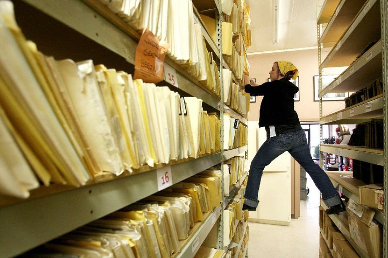 
Bekah Cone pulls a file of old photos from the shelf as she searches for an original print to ship to an Ebay buyer at the John Rogers Photo Archives  along North Poplar Street in North Little Rock Wednesday. 