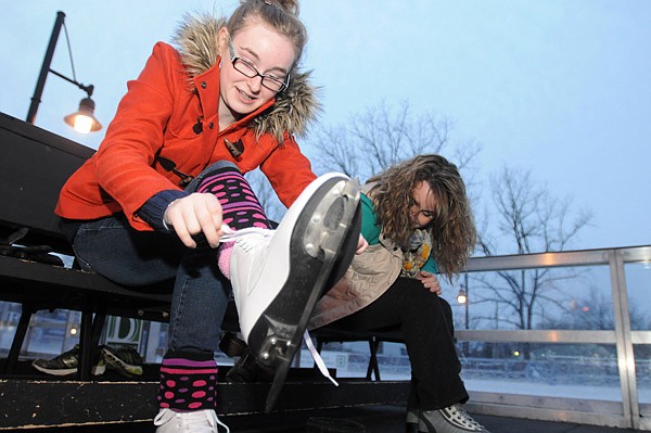 Amanda Mandras, right, sits next to her daughter, Tegan Mandras, 13, as they lace up their ice skates Wednesday at The Rink at Lawrence Plaza in downtown Bentonville. The temporary ice skating rink closes Jan. 20. 