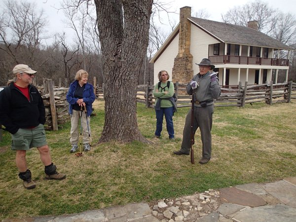 Heter, Chodrick and Heter listen to historian Dave Lewis reveal details about the Battle of Pea Ridge. A replica of Elkhorn Tavern, which served as a battlefield hospital, is behind Lewis. 