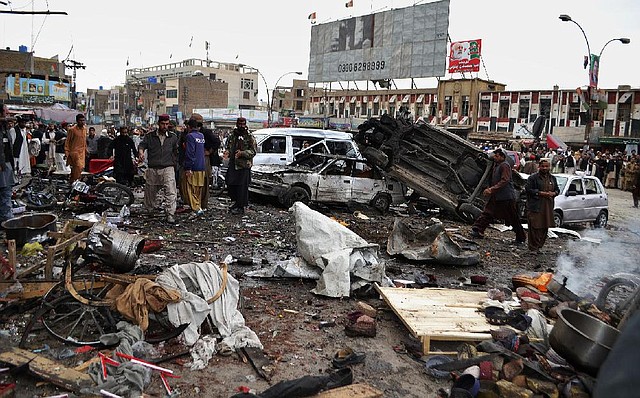 Pakistani police and others work at the scene of a bombing in Quetta where at least 12 people were killed. 