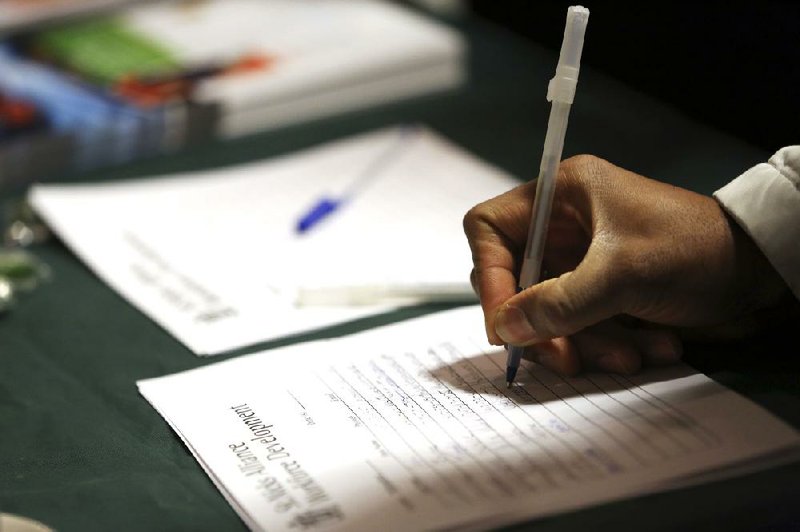 A job seeker lists information with a potential employer at a job fair in New York in December. Applications for unemployment benefits rose slightly last week, the Labor Department said. 