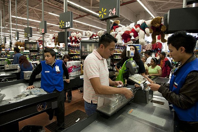 A man checks out at a cash register at a Wal-Mart store in Mexico City in this ÿle photo. Wal-Mart Stores Inc.’s Chief Executive Officer Mike Duke was told in 2005 that the retailer’s Mexico unit was bribing Mexican officials, according to e-mail messages obtained by lawmakers. 