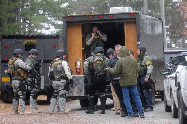 The Benton County Sheriff’s Office SWAT team gears up to work a standoff Thursday on Hickory Lane in the Beaver Shores community near Rogers. 