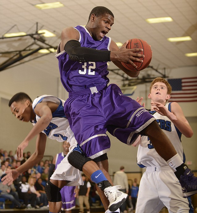 Fayetteville’s Manuale Watkins, center, grabs a rebound over Rogers’ Xavier Smith, right, and Jake Killingsworth during Friday’s game at King Arena in Rogers. 