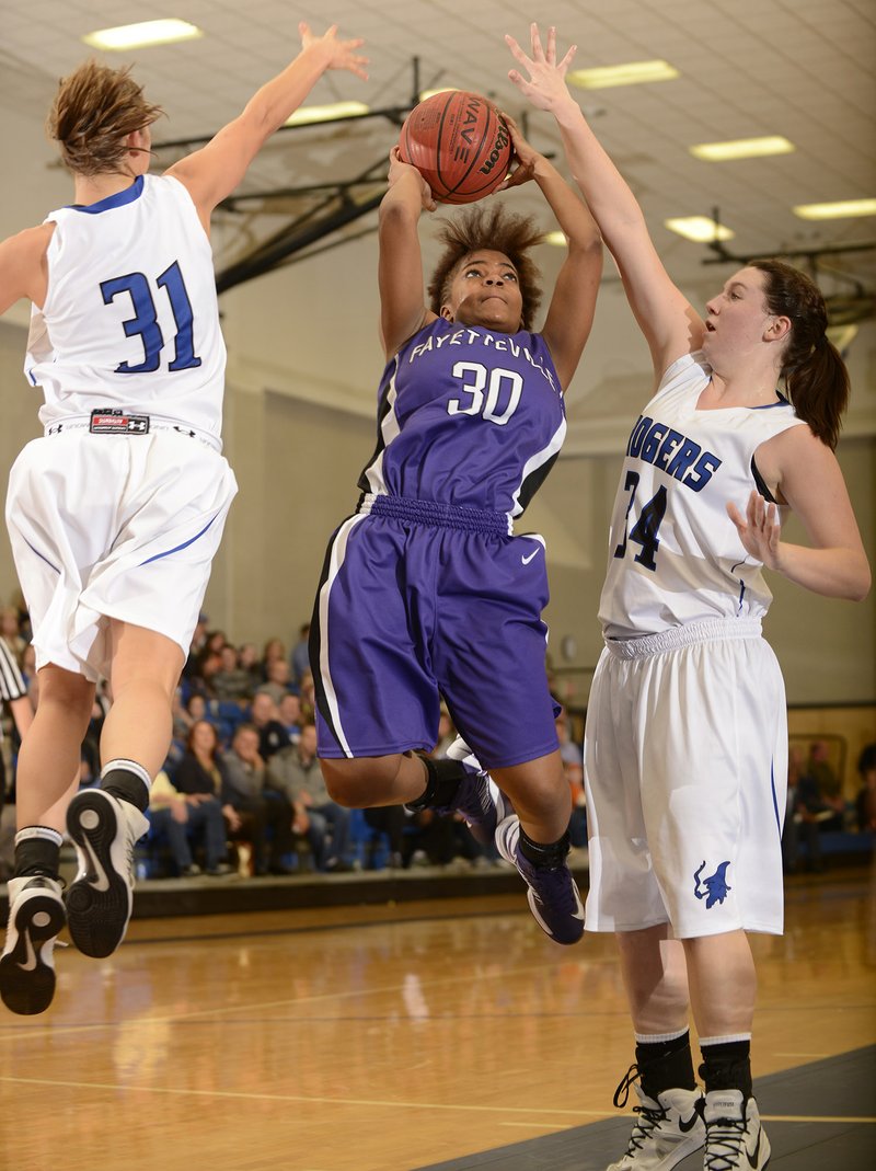 Fayetteville’s Catara Robinson, center, makes a jump shot between Rogers’ McKinzie James, left, and Samantha Warren during Friday’s game at King Arena in Rogers. 