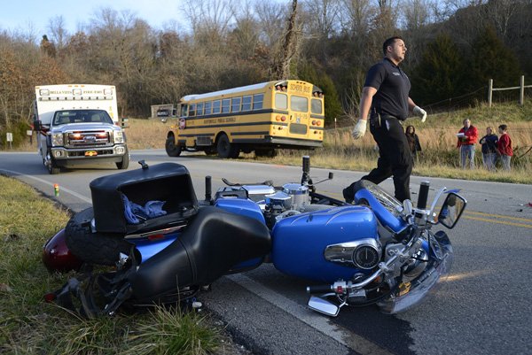 Bella Vista firefighter Lucas Clemmons works the scene of an accident Friday between a motorcycle and a Bentonville school bus on East McNelly Road near Rolling Hills Drive in Bentonville. 