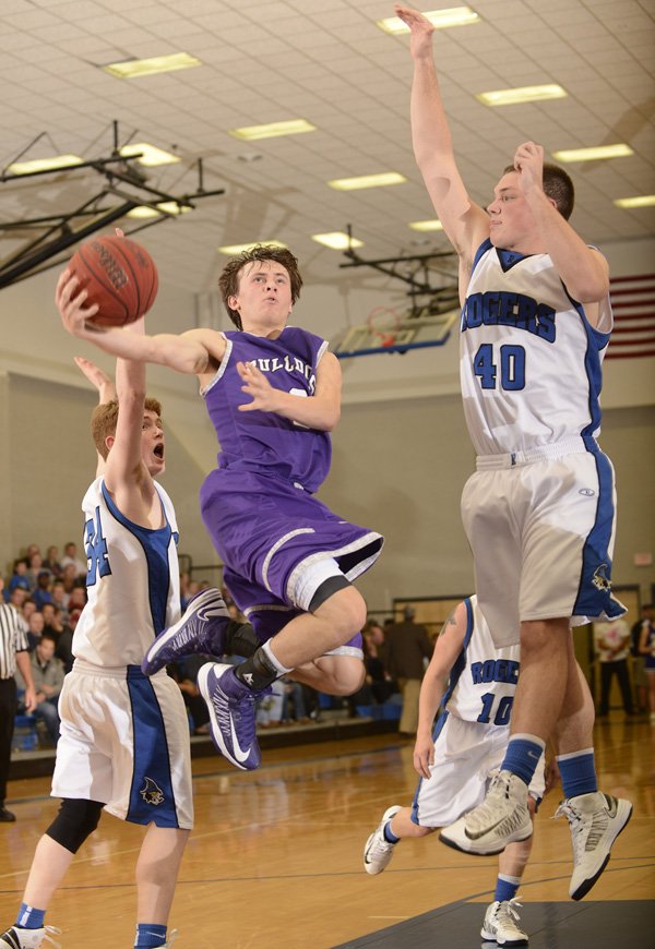 Cameron Paschke, center, Fayetteville, takes the ball to the basket between Rogers High’s Jake Killingsworth, left, and Brett Gentz on Friday at King Arena in Rogers. 