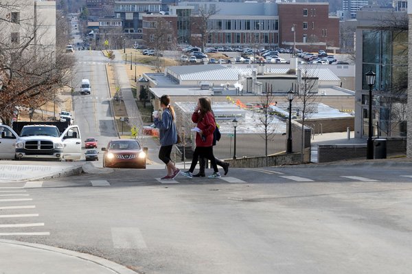 Pedestrians cross Dickson Street Friday near the University of Arkansas in Fayetteville. The city of Fayetteville has granted the university a permit to limit the amount of traffic on Dickson Street from Harmon Road to Garland Avenue for specific times during the week.