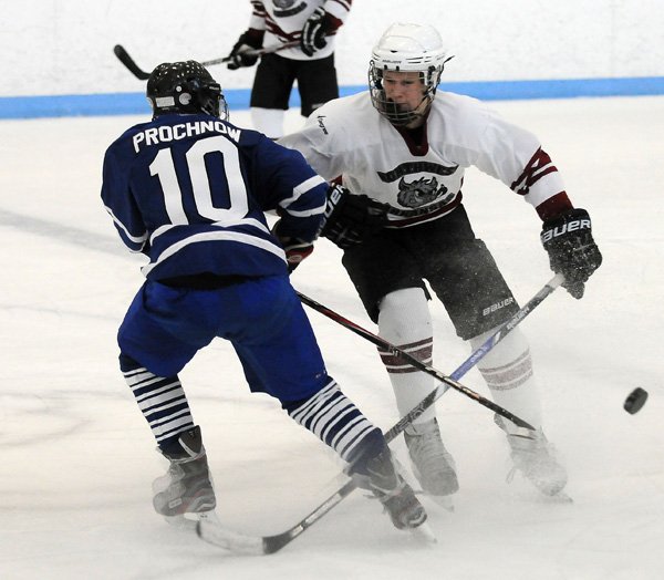 Weston Easley, right, with the Northwest Arkansas Ice Hogs checks Connor Prochonow of Rockhurst High School in Kansas City, Mo., on Sunday during day two of play at the Jones Center in Springdale. Easley scored the only goal of the game for the Ice Hogs. The Ice Hogs, coming off their first lost yesterday, lost again to Rockhurst, 5-1. The Ice Hogs are the Mid-America High School Hockey League defending champions and is comprised of players from around the state. 