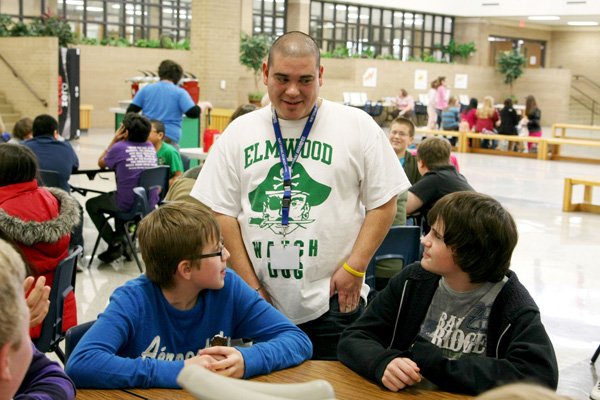 James Sandoval, Elmwood Middle School volunteer, talks Thursday with seventh-graders Eli Crawford and Brandon Mason during lunch at Elmwood in Rogers. Sandoval attended Elmwood. 