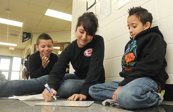 Magnolia Bahena, 16, Springdale High School junior, works on a spelling list Friday with George Elementary students Edward Vasquez, 8, left, and Michael Bandera, 8. Bahena is with Springdale’s Delta group, which performs various community service projects in the area, including acting as mentors to the elementary students. 