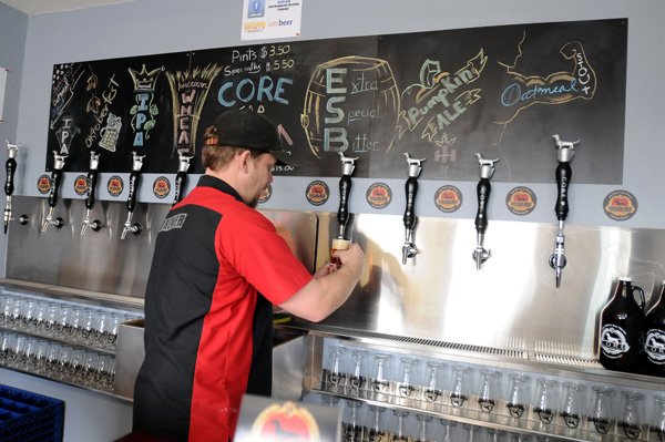 Jesse Core pours a sample beer Friday at his microbrewery, Core Brewing Company, in Springdale. The opening of the microbrewery is one of the latest examples of growth and redevelopment in Springdale. 