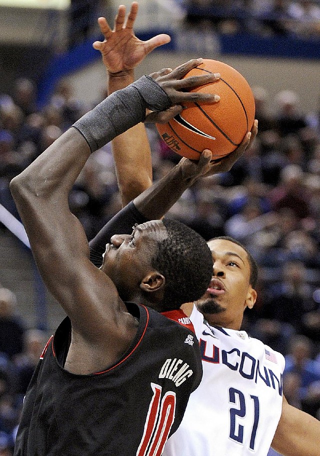 Louisville’s Gorgui Dieng (left) is guarded by Connecticut’s Omar Calhoun in the Cardinals’ 73-58 victory over the Huskies. 