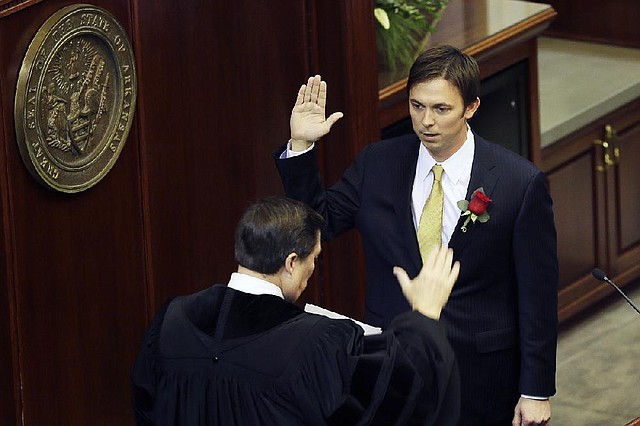 Standing before Arkansas Chief Justice Jim Hannah, state Rep. Davy Carter (right) takes the oath of office Monday in the House chambers at the state Capitol in Little Rock. Carter’s colleagues selected the Cabot Republican to be their House speaker. 