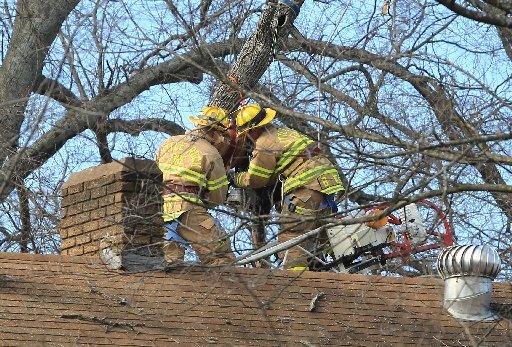 Little Rock firefighters work to get a man, with Hernandez Tree Service, down after he was killed by coming in contact with electric lines while trimming tree limbs behind a house in the 3600 block of West 10th St. around 1 pm Wednesday.