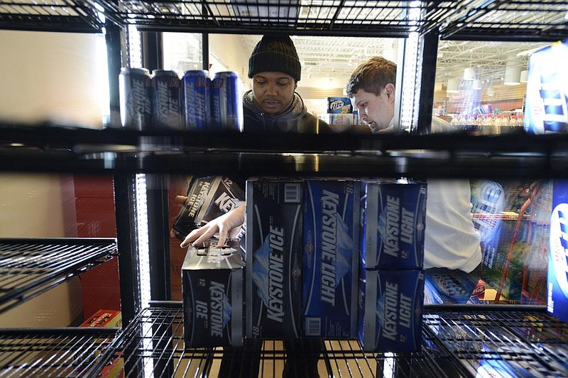 Keon Boles, left, and Kevin Owens with Premium Brands of Northwest Arkansas stocks the shelves Wednesday, Jan. 16, 2013, at Kum & Go store No. 408 on East Central Avenue in Bentonville. (NWA Democrat-Gazette/FILE PHOTO)