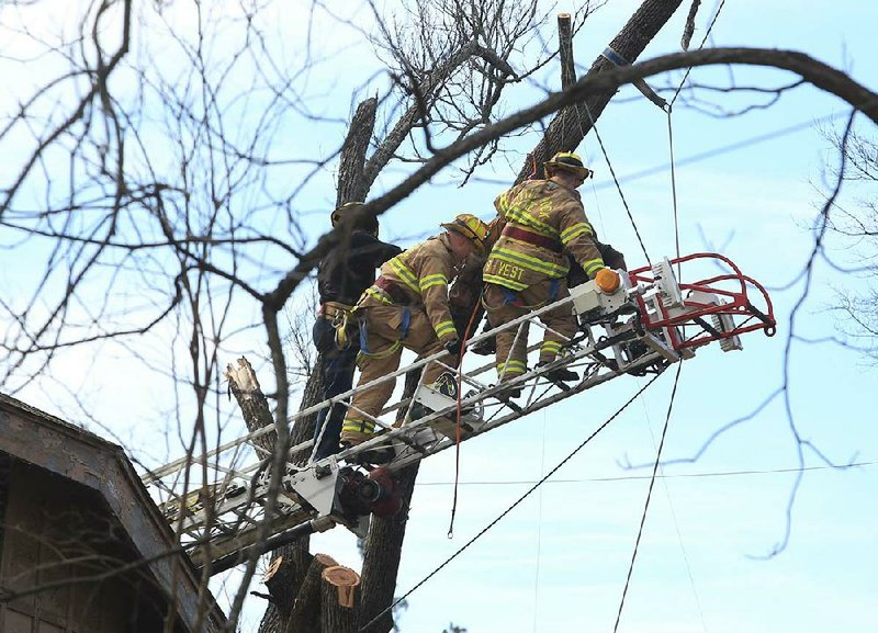  Little Rock firefighters work to get a man, with Hernandez Tree Service, down after he was killed by coming in contact with electric lines while trimming tree limbs behind a house in the 3600 block of West 10th St. around 1 pm Wednesday.