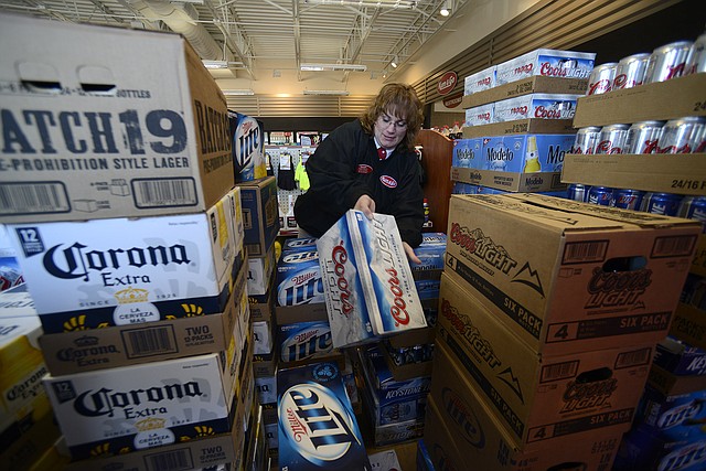 Barb Trusty, general manager for Kum & Go store No. 408, sorts through cases of beer Wednesday, Jan. 16, 2013, while getting her store on East Central Avenue in Bentonville stocked and ready to sell the alcoholic beverages beginning at 7 a.m. Thursday.