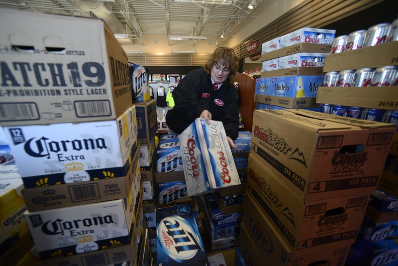 Barb Trusty, general manager for Kum & Go store No. 408, sorts through cases of beer Wednesday, Jan. 16, 2013, while getting her store on East Central Avenue in Bentonville stocked and ready to sell the alcoholic beverages beginning at 7 a.m. Thursday.