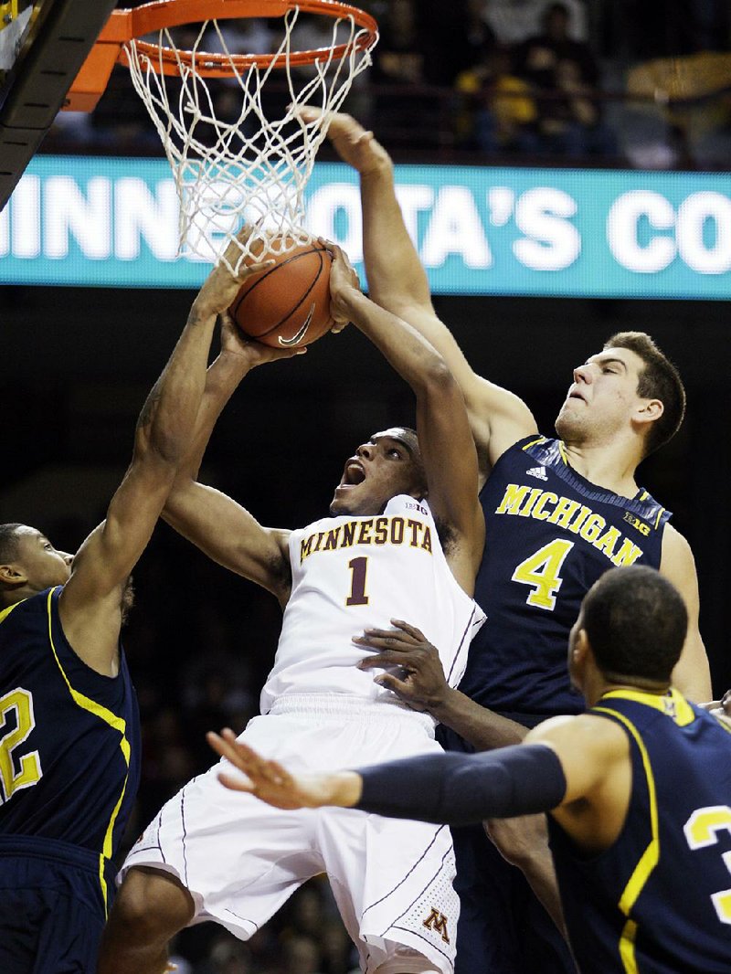 Minnesota guard Andre Hollins (1) is fouled by Michigan forward Mitch McGary (4) as he tries to shoot in a crowd during the second half of Thursday’s game in Minneapolis. Michigan won 83-75. 