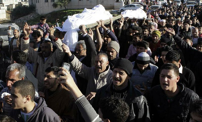 Syrians and Jordanians mourn seven members of a Syrian family who died Wednesday night in a ÿ re at a refugee-processing center in Ramtha, Jordan. 