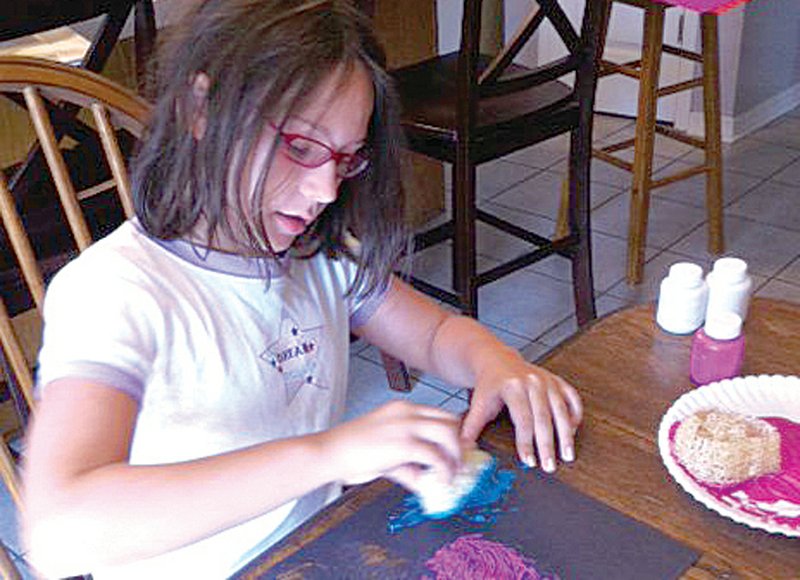 Victoria Staton, daughter of Lufa Life founder Cathy Staton, creates a painting with slices of loofah sponge. Cathy sells pre-made sponge-painting kits to raise money for the organization.